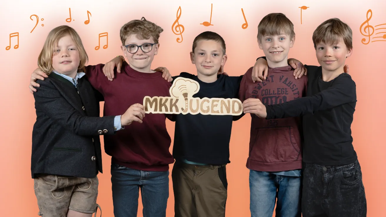 Fünf Kinder stehen Arm in Arm vor orangem Verlauf mit Notensymbolen und halten gemeinsam ein MKK Jugend Schild.
