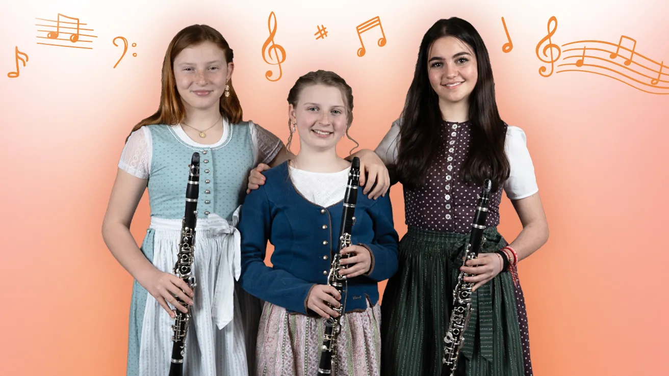 Drei Jugendliche vor orangem Verlauf mit Notensymbolen. Alle halten eine Klarinette in der Hand und tragen Tracht.
