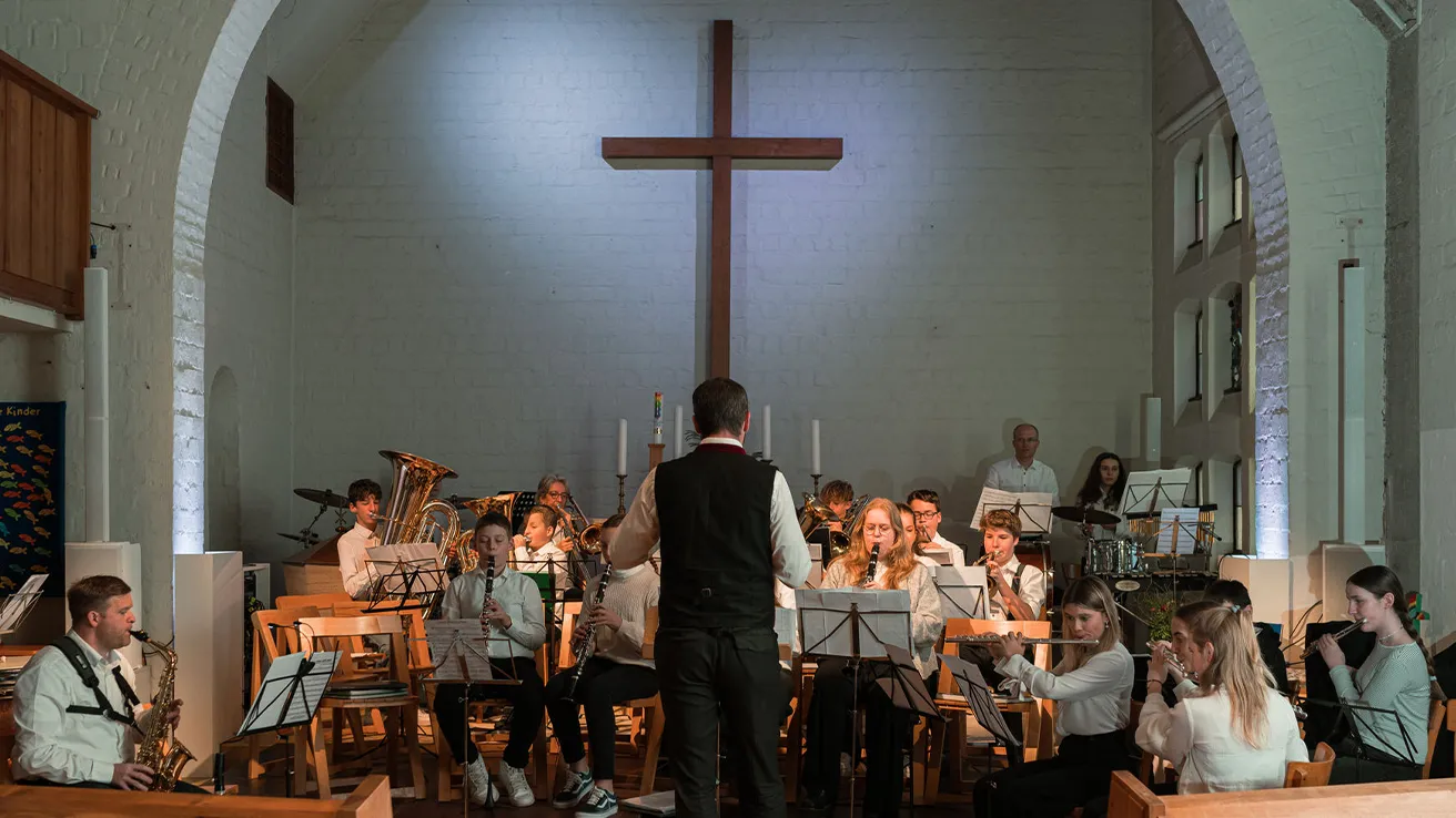 Jugendorchester spielt in einer Kirche unter der Leitung eines Dirigenten.
