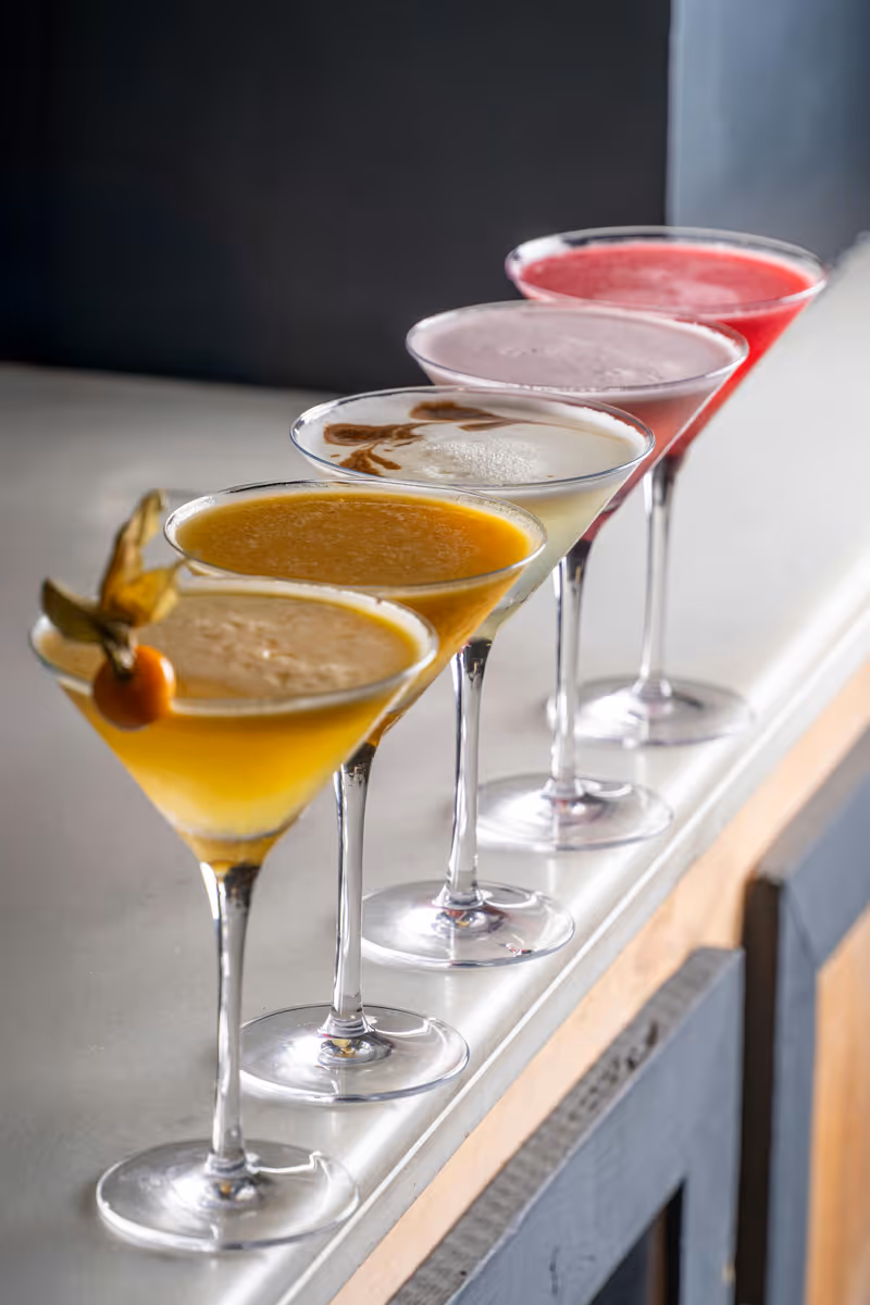 Four Madame Mocktail zero-proof signature flavors served in elegant martini glasses with fruit garnishes