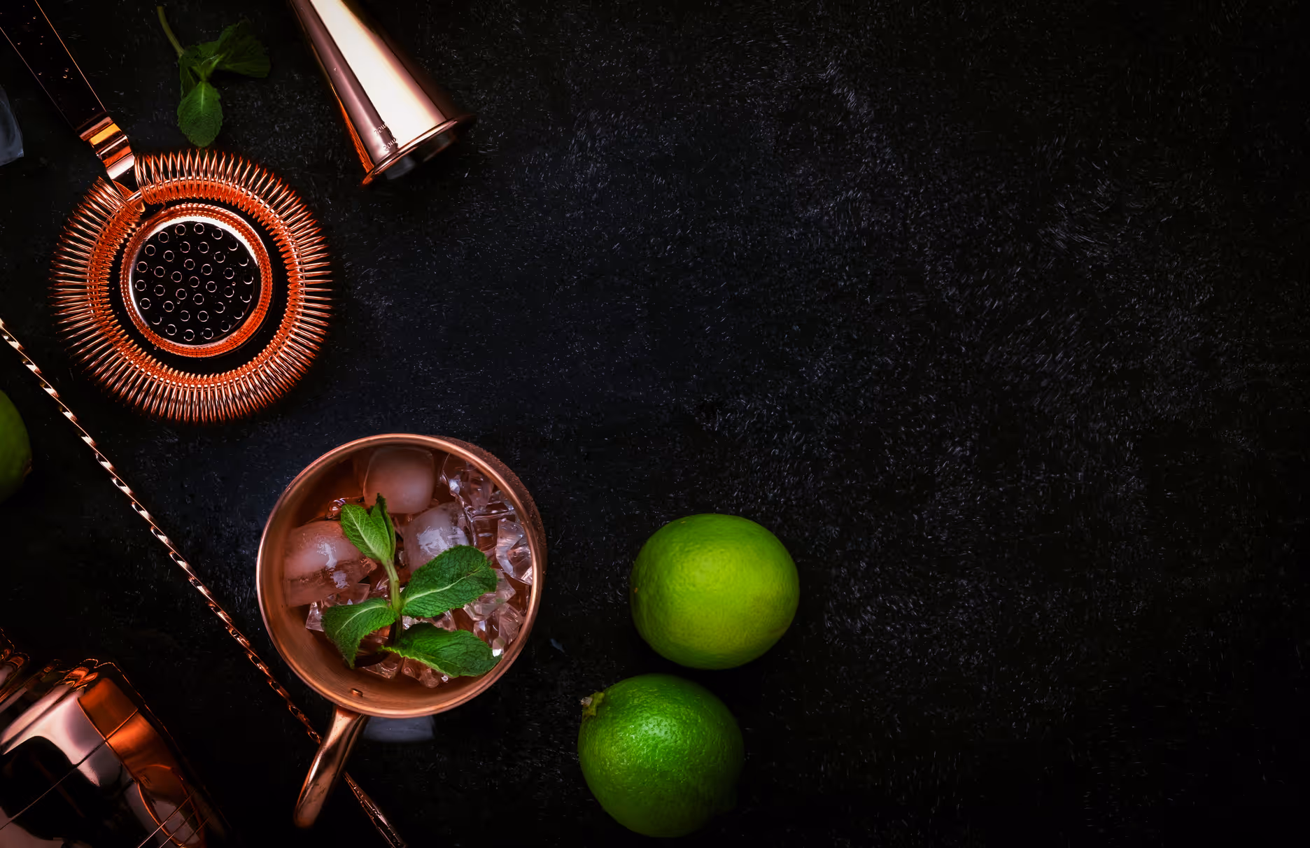 Madame Mocktail Black Cherry Moscow Mule in a copper mug with fresh mint and lime garnish surrounded by bar tools