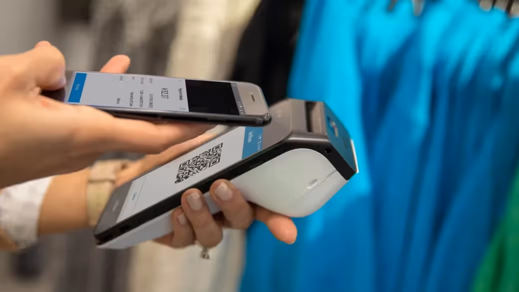 Person using a mobile phone to make a payment with QR code on a credit card machine