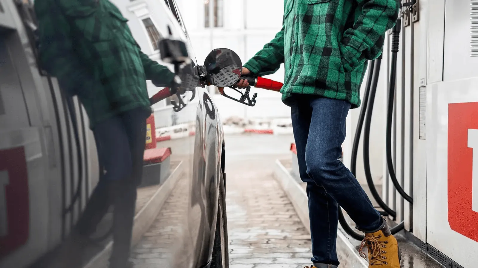 Photo of a man in a gas station putting fuel in his car