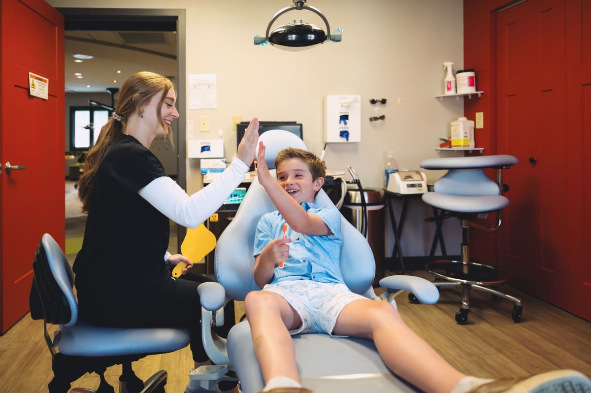 Pediatric dentist examining a young patient in the dental chair during treatment