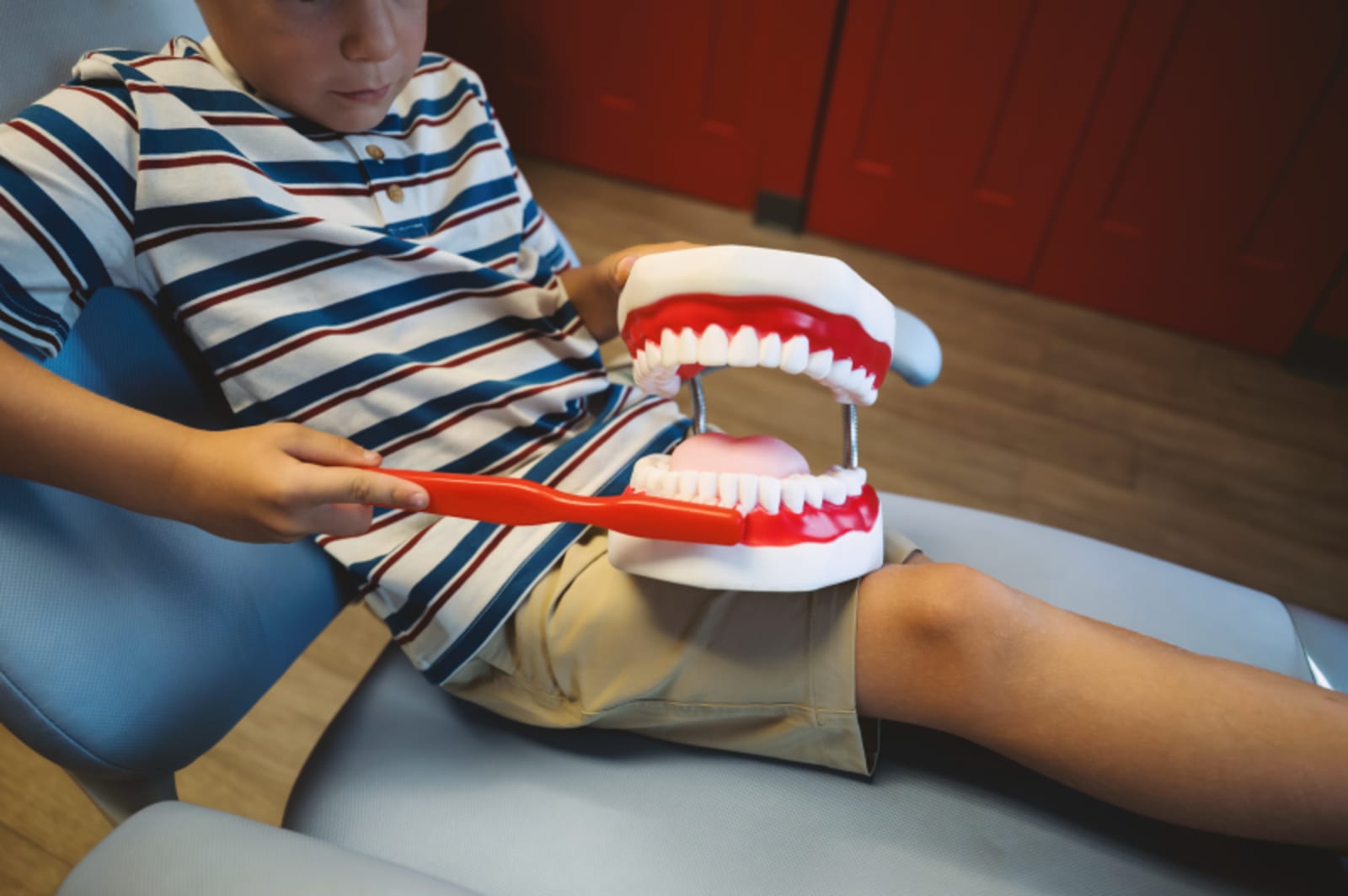 Pediatric dentist showing dental model to young patient during treatment discussion