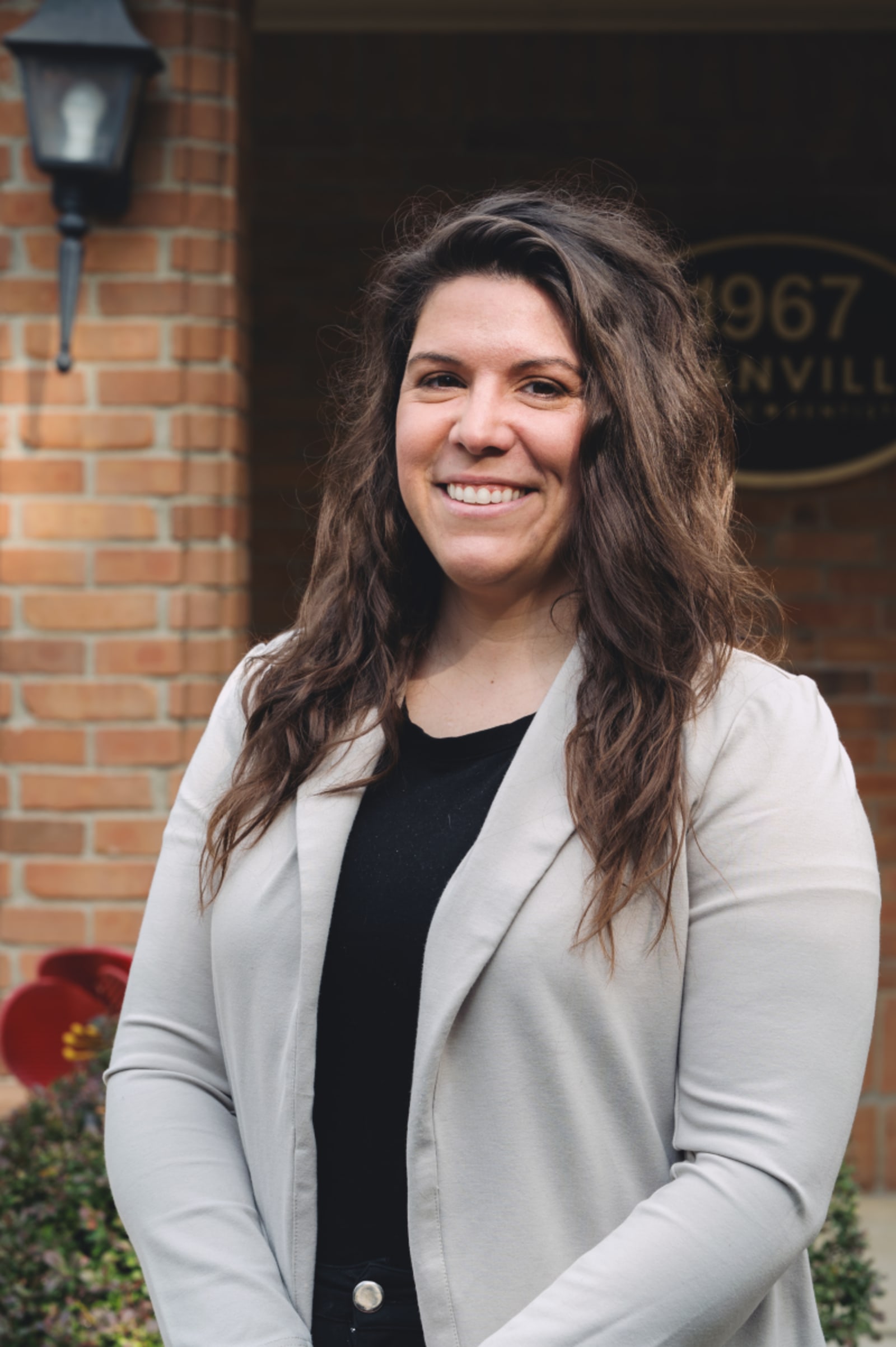 Female dentist smiling outside the practice entrance, appearing friendly and approachable