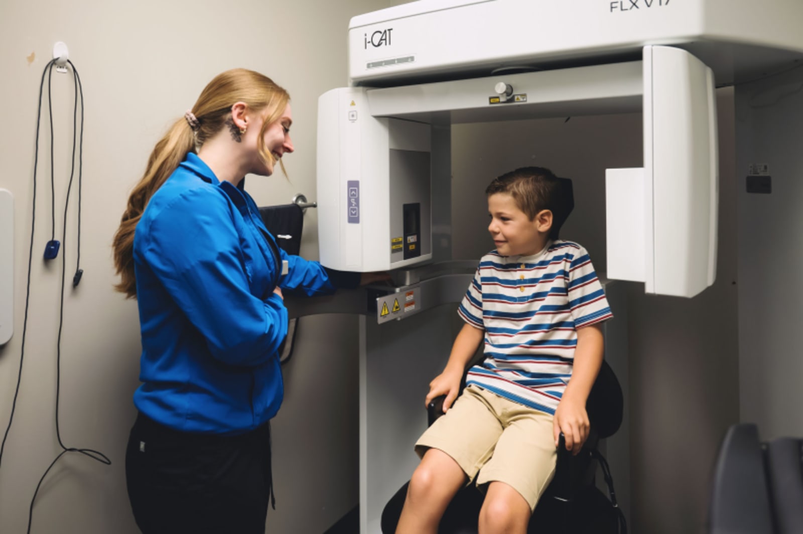 Pediatric dentist taking dental X-rays of young patient in treatment room.