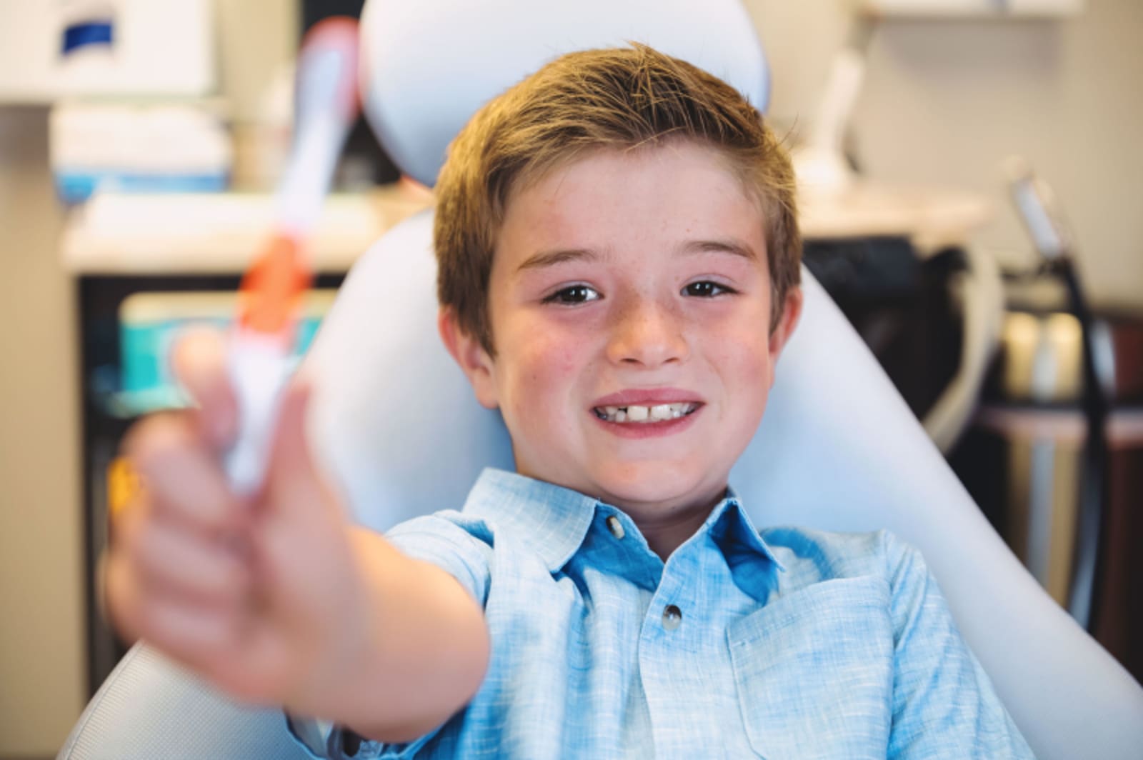 Young girl with glasses smiling in dental treatment chair during checkup