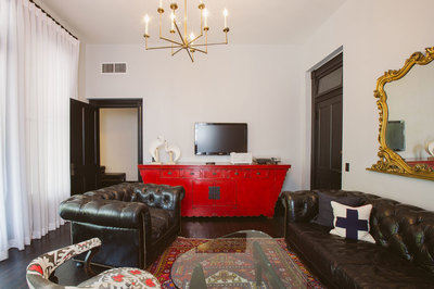 A cozy suite with a red side table adorns the living space with leather couches and luxury decor.
