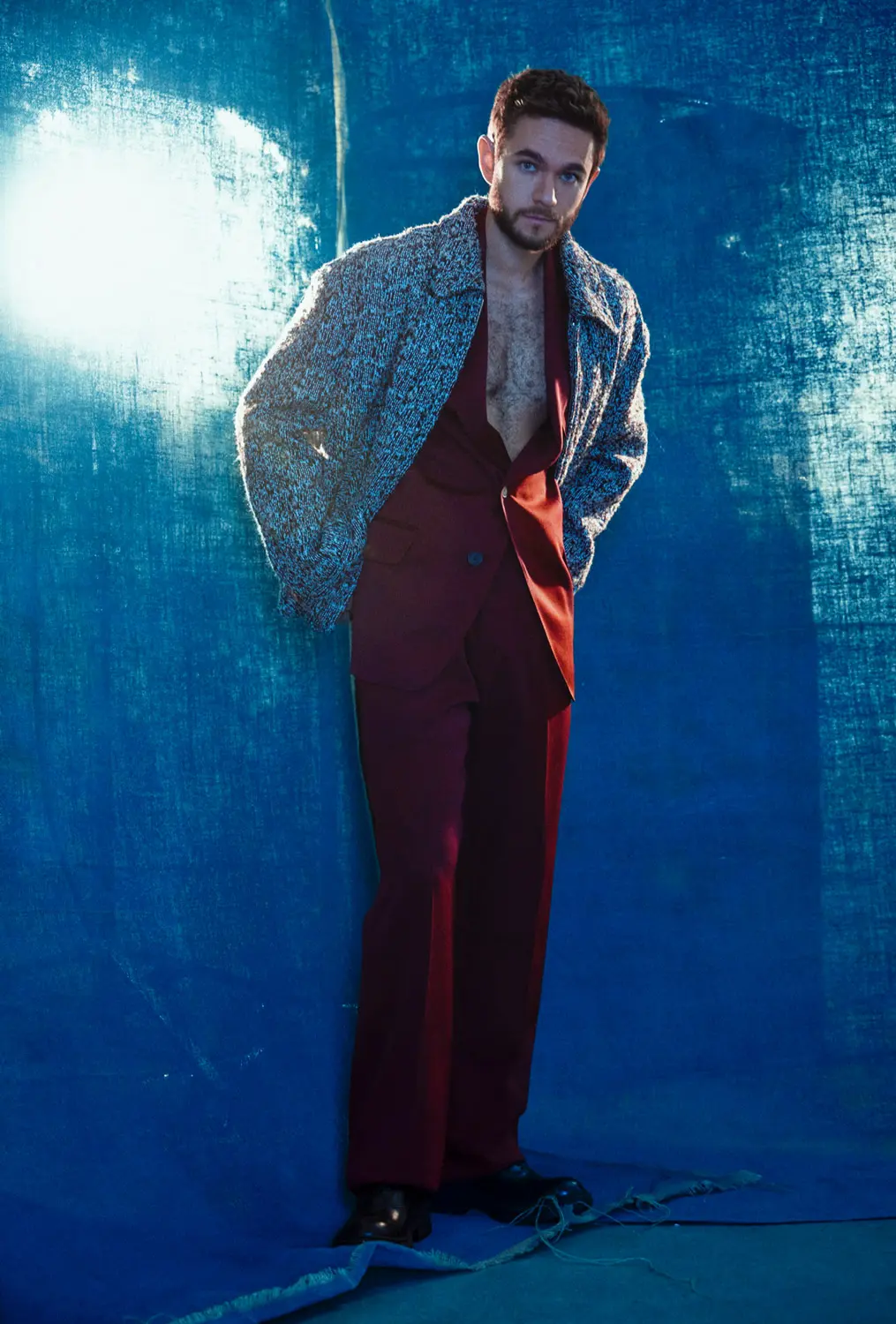 Stylized editorial shot of a man in a burgundy suit and textured coat, fashion direction by Sepulveda Studios.