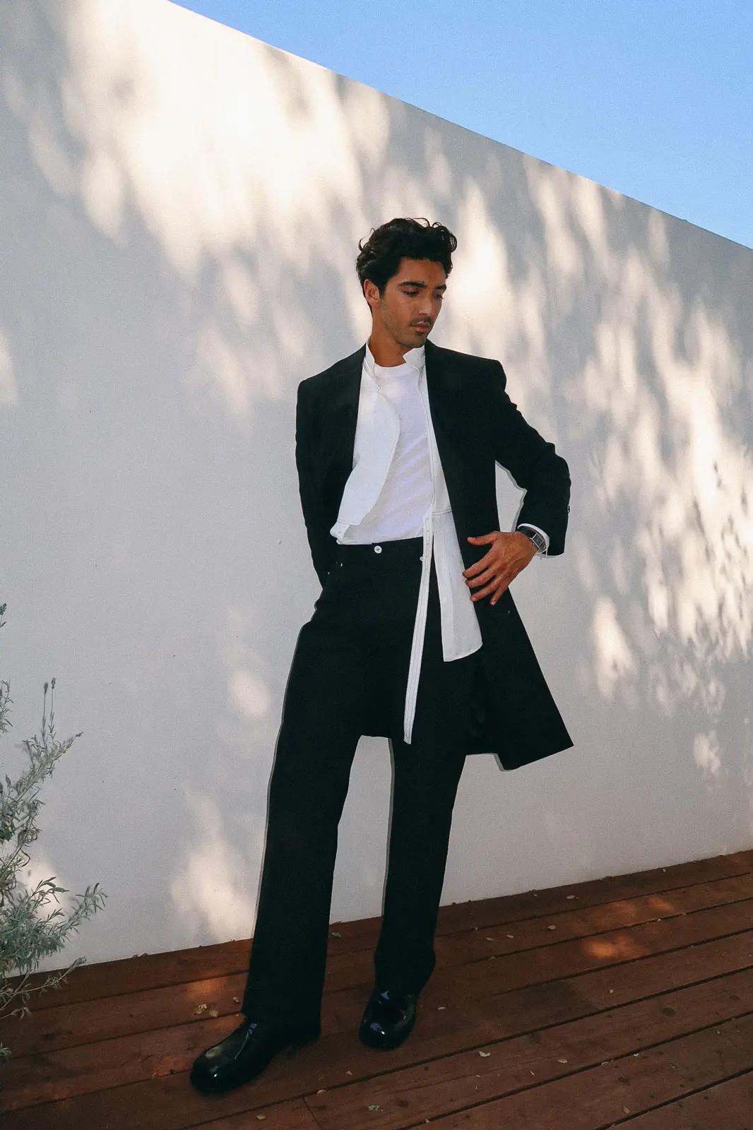 A modern menswear portrait featuring layered black tailoring and soft natural light. Photographed by Sepulveda Studio, this look plays with proportion and shadow for a clean, elevated visual.