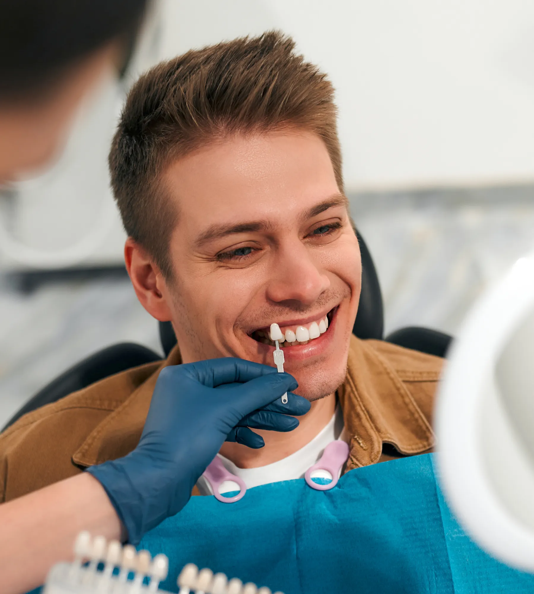 A dentist matches a patient's tooth color with a shade guide during a dental appointment.