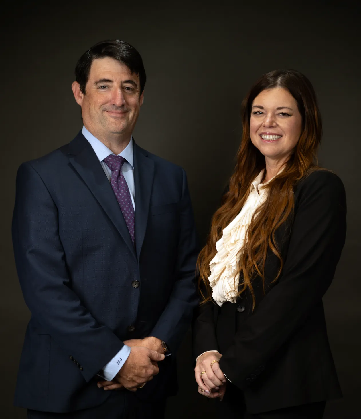 Professional business portrait of two smiling colleagues in formal attire