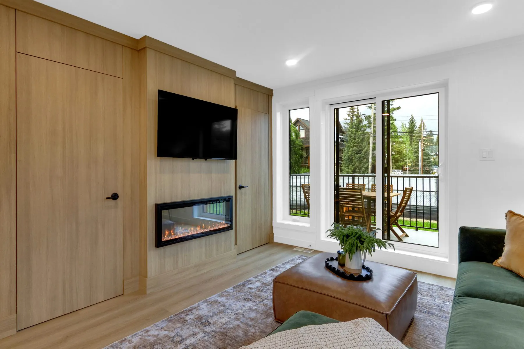 The living room and fireplace of a home at Colliery Parc in South Canmore, with doors opening onto the deck