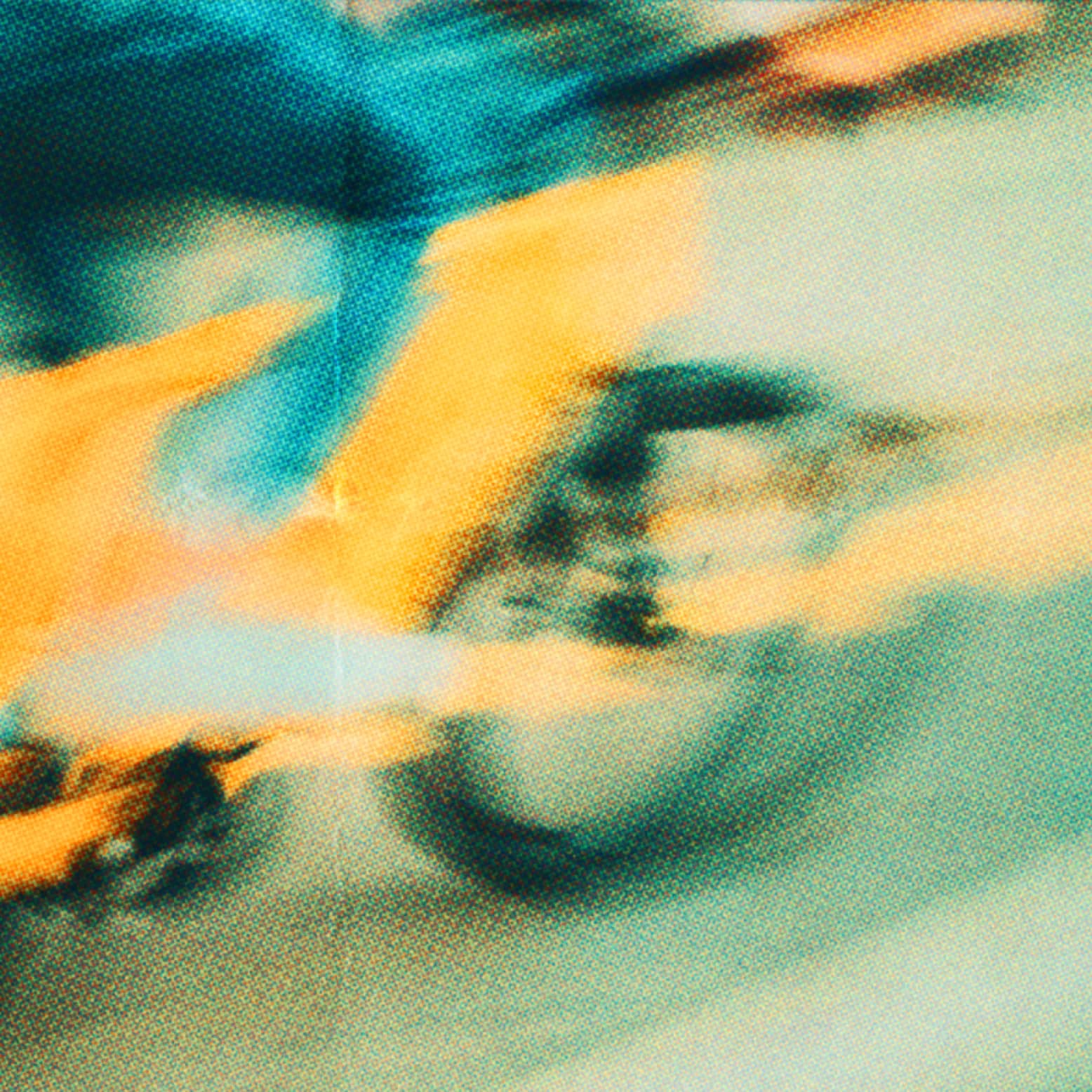 Blurred close-up image of a cyclist in yellow and blue clothing riding a bicycle, conveying motion and speed.
