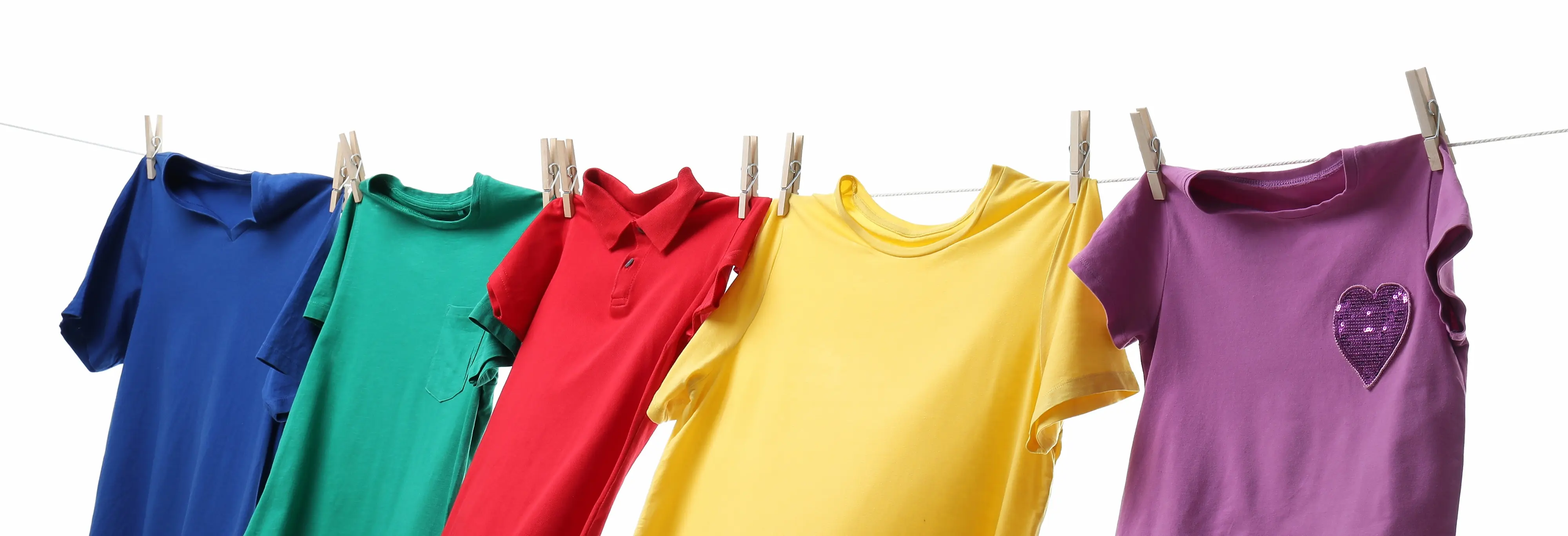 Cinq t-shirts colorés accrochés à une corde à linge avec des pinces en bois, couleurs bleu, vert, rouge, jaune et violet.