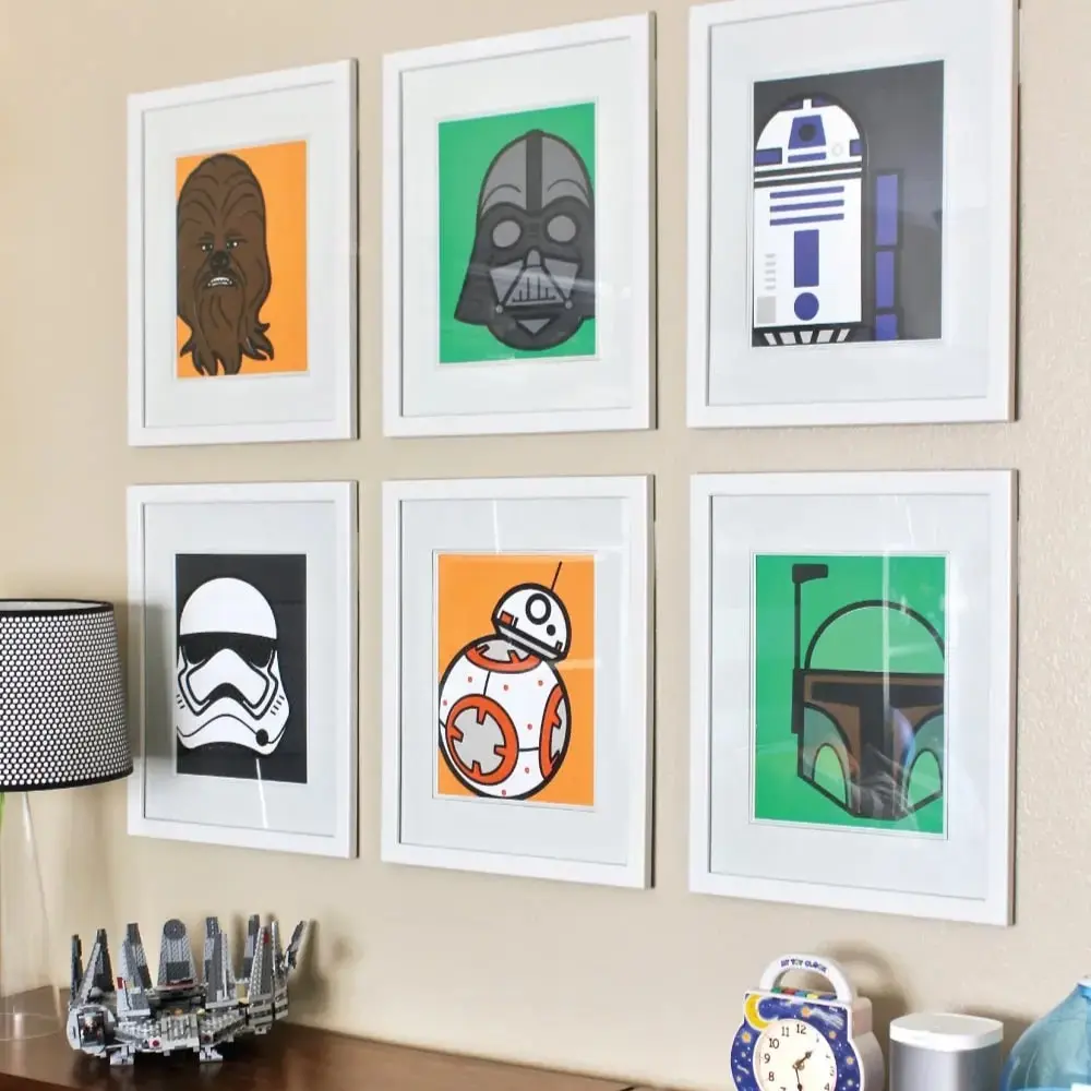 Six illustrations encadrées de personnages Star Wars, accrochées sur un mur au-dessus de deux commodes en bois.