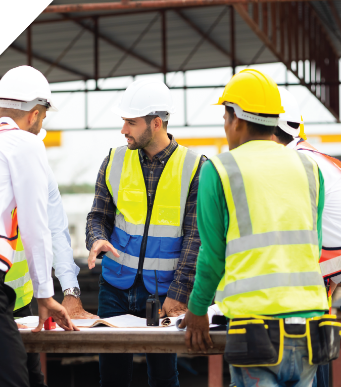 Three men in high-vis work wear, standing around a table talking
