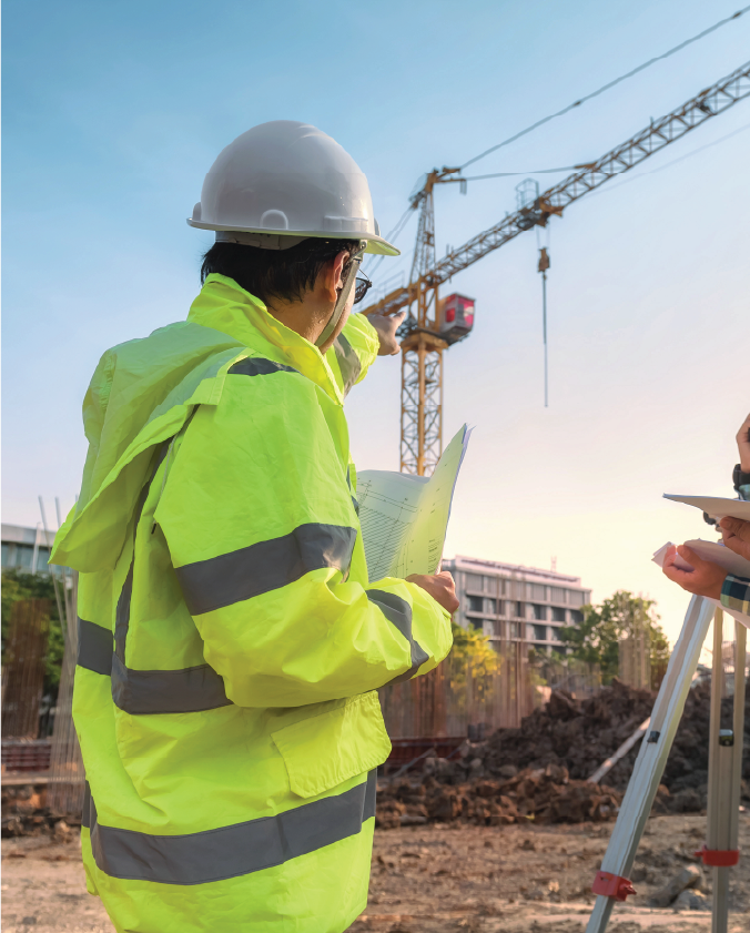 A behind view of a construction worker pointing towards a crane 