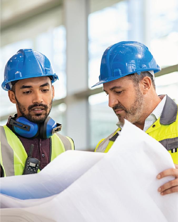 Two construction workers looking over blueprints. 