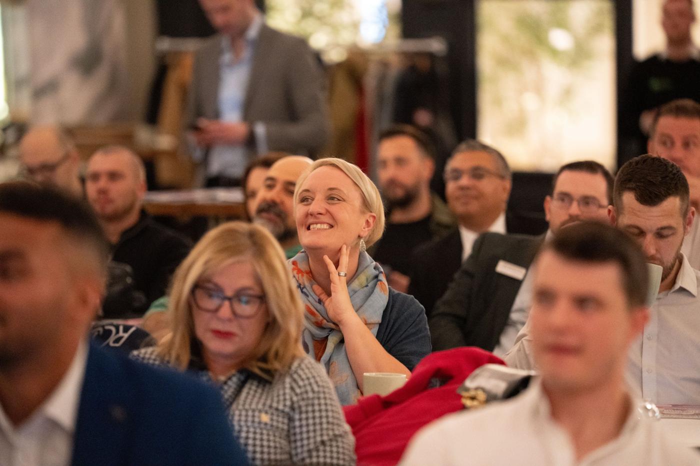A delegate smiling in the audience at a Blue Bricks event