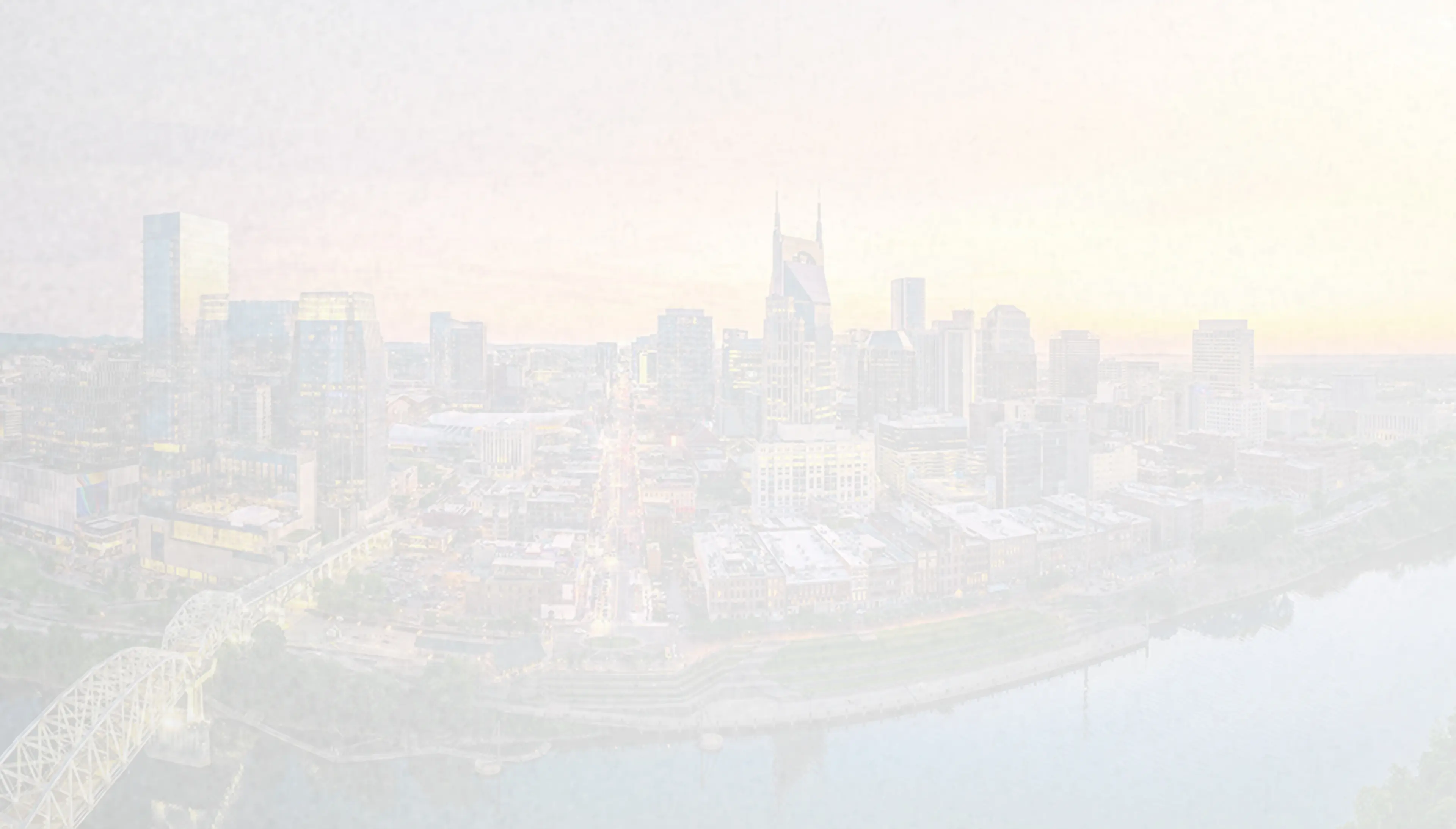 Panoramic view of downtown Nashville, Tennessee, at sunset featuring the John Seigenthaler Pedestrian Bridge and city skyline reflecting over the Cumberland River — the heart of country music and Dolly Parton’s hometown state.