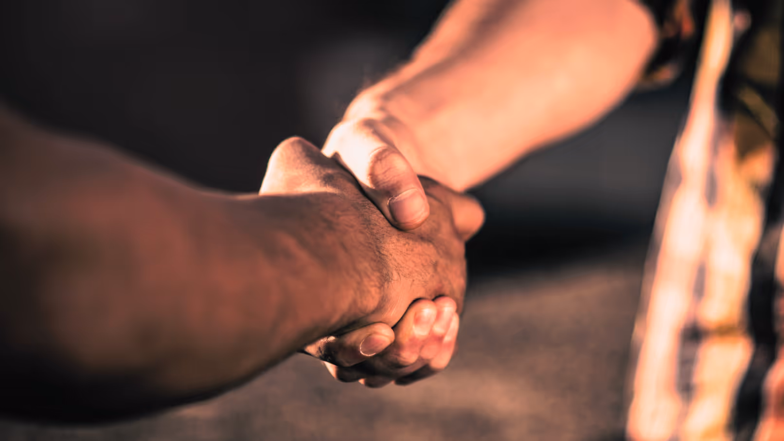 Firm handshake between two trades professionals in a jobsite setting, representing trust and long-term planning.