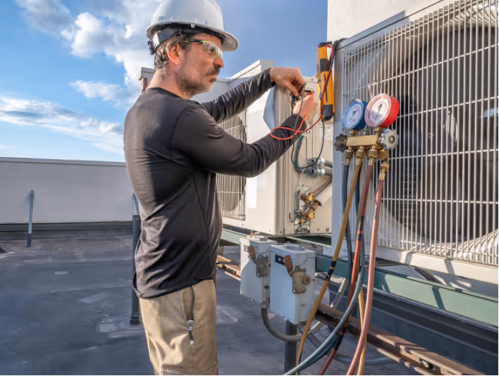 Commercial and residential HVAC owner Sam diagnosing a rooftop condenser unit on a commercial building.