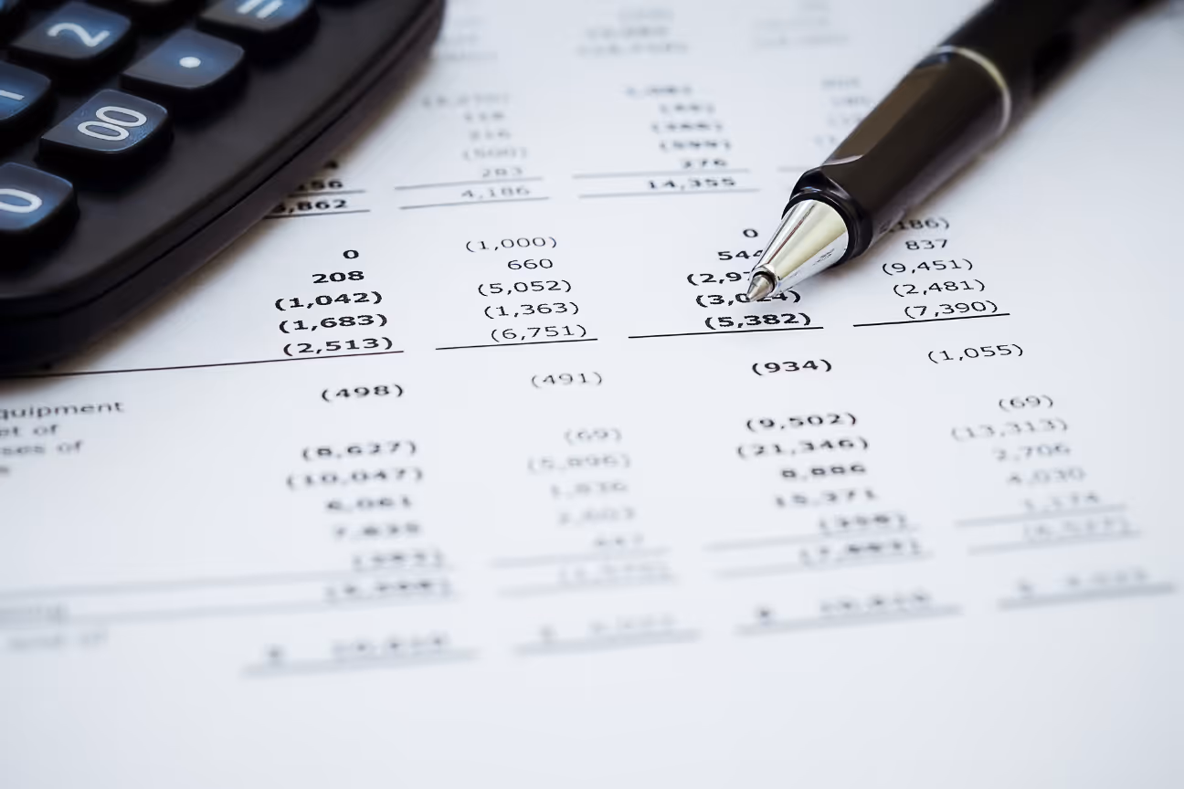 Financial paperwork with a calculator and pen showing margin and job cost calculations.