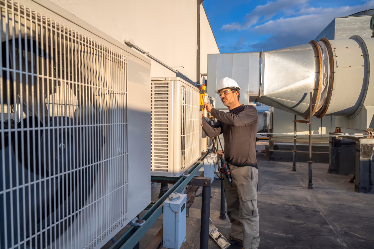 HVAC technician working on a wall-mounted outdoor unit at a residential jobsite.