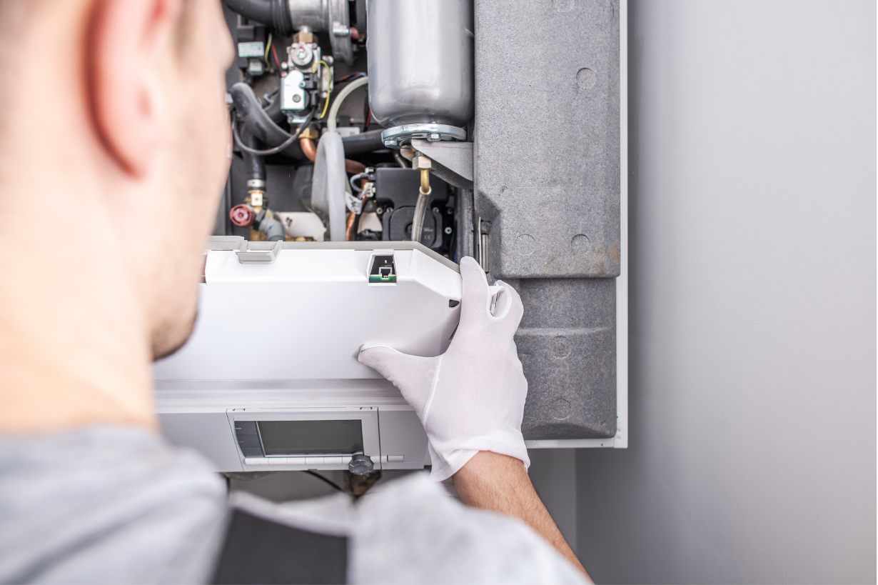 An HVAC tech wearing gloves is working on a commercial unit.
