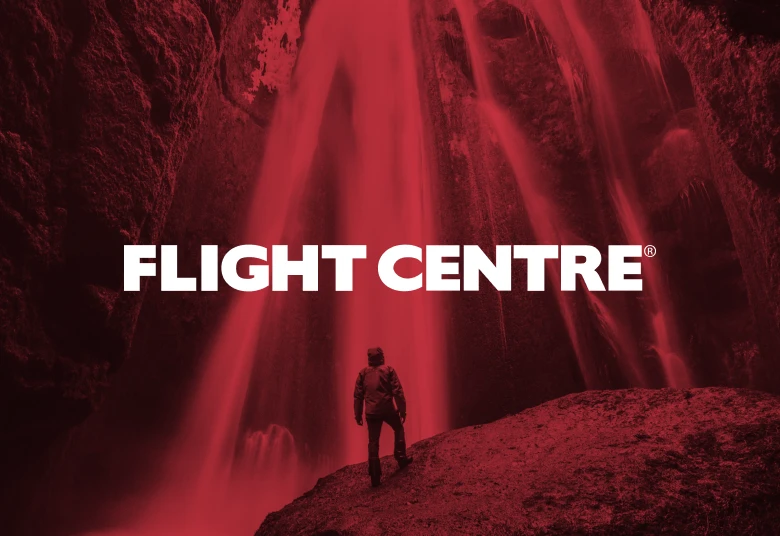 Flight Centre logo over a red-tinted image of a hiker standing beneath a waterfall