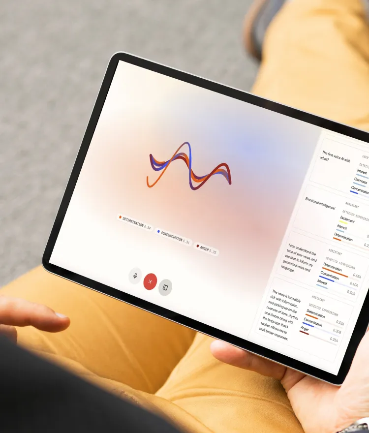Person holding a tablet displaying a voice emotion analysis interface with a colorful waveform and emotional metrics like determination, concentration, and anger.