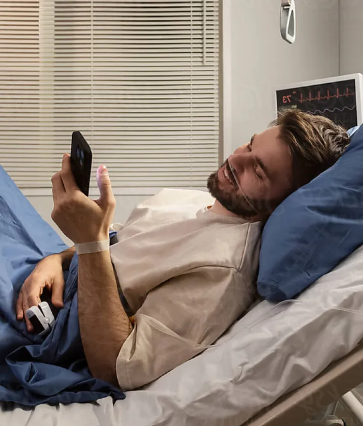 A man in a hospital bed, using his smartphone to stay connected during his recovery