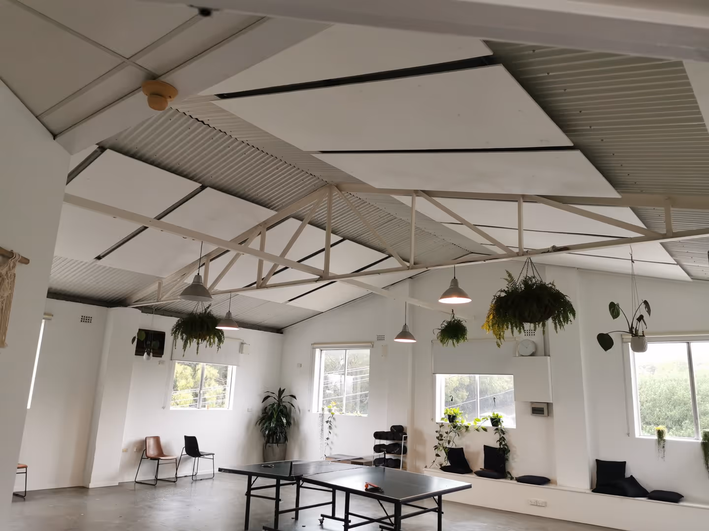 Modern open-plan studio featuring integrated white acoustic ceiling panels for sound treatment, reducing echoes in a high-ceiling space.