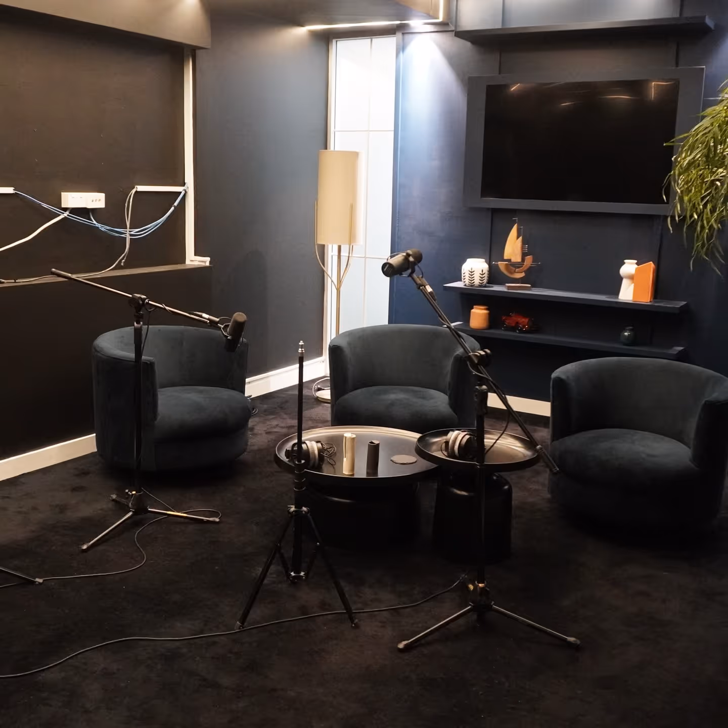 Acoustically treated media room and podcast studio with professional audio equipment, navy velvet seating, and minimalist interior design.
