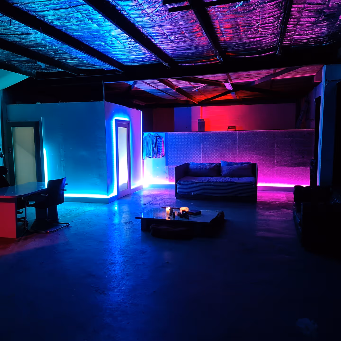 High-contrast modern lounge with blue and red LED lighting and a textured metal ceiling, incorporating multiple types of sound diffusion for a unique architectural experience.