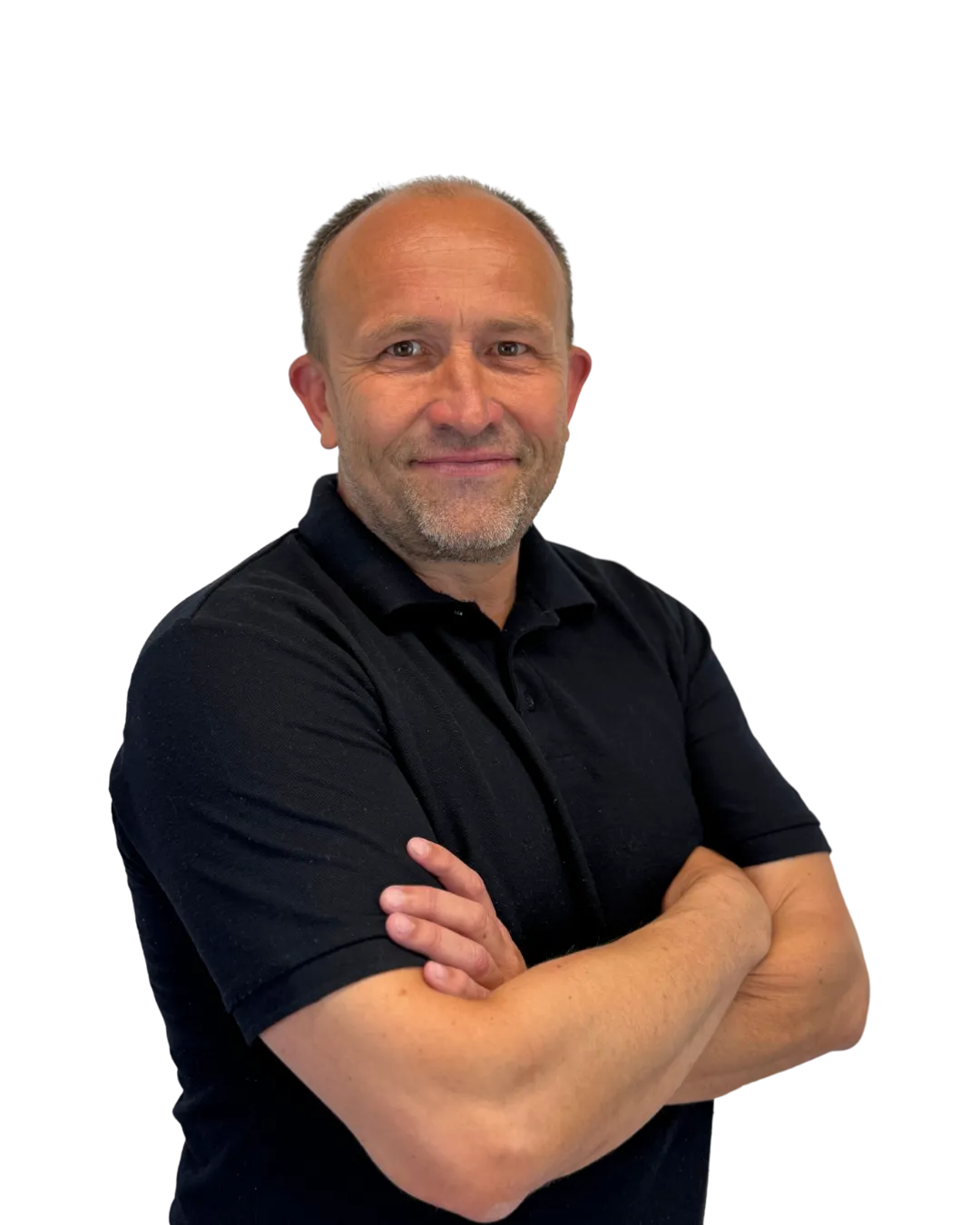 Smiling middle-aged man with short hair and beard, wearing a black polo shirt, standing with arms crossed.