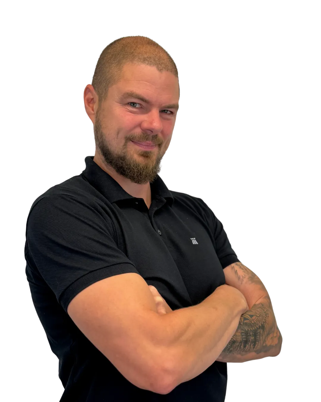Man with short hair and beard wearing a black polo shirt with arms crossed, showing tattoos on his left forearm.