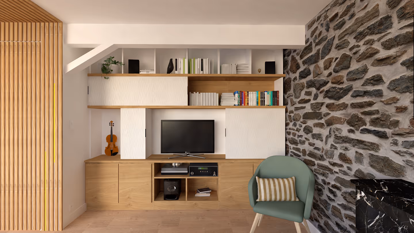Une pièce avec un mur en pierre et meuble télé en bois sur-mesure bien organisé.