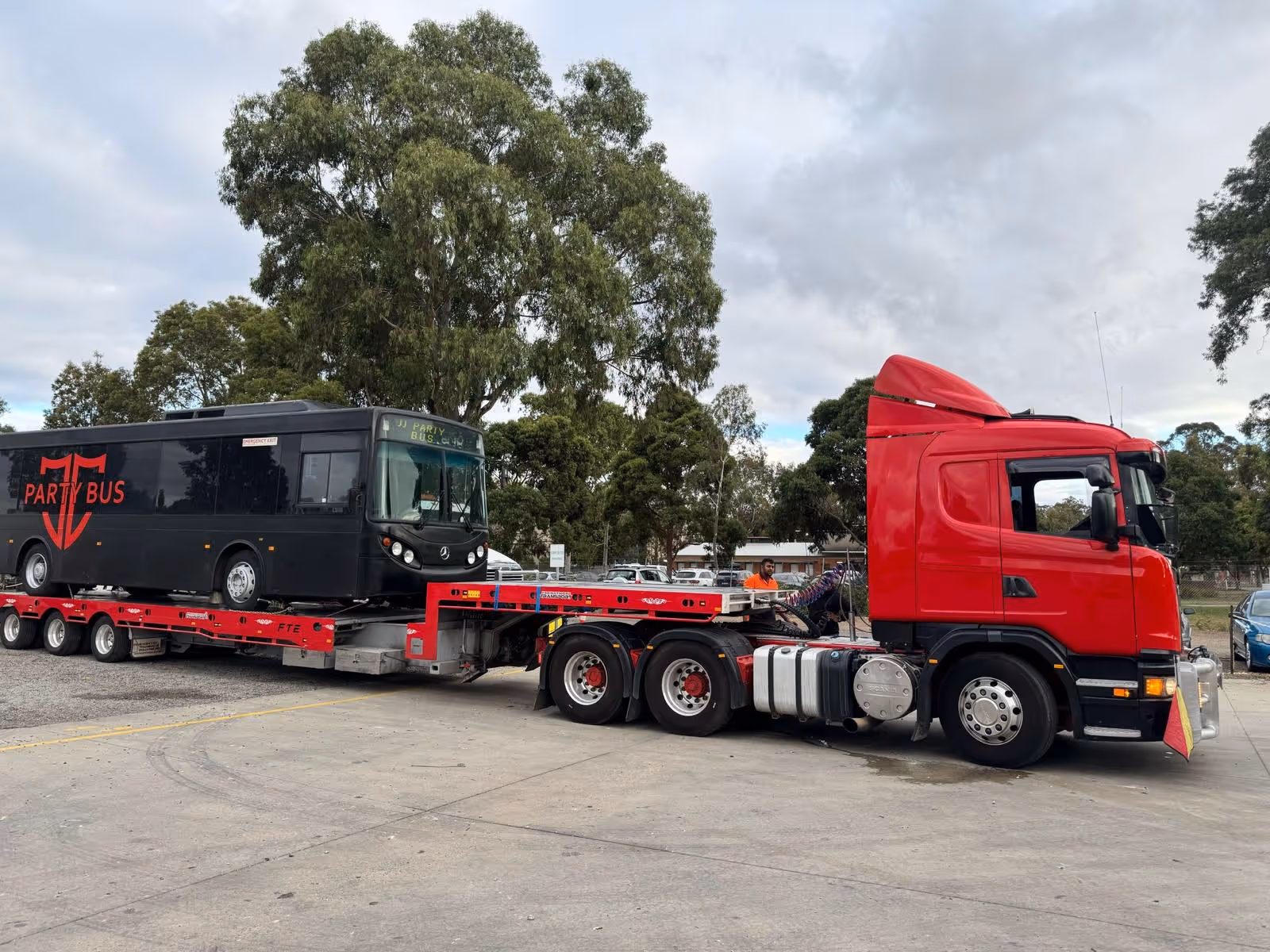 a truck with a black vehicle on a flatbed trailer