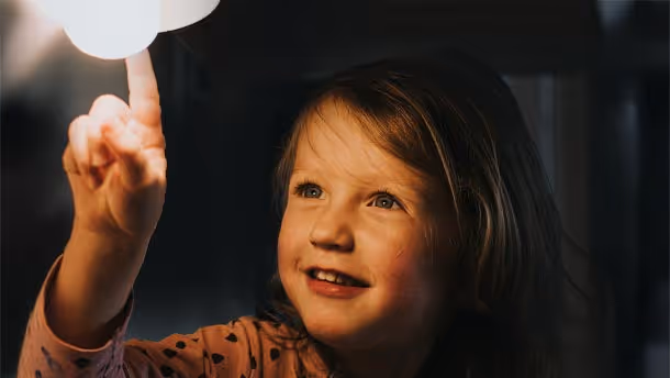 Kind berührt mit Finger Nachtischlampe