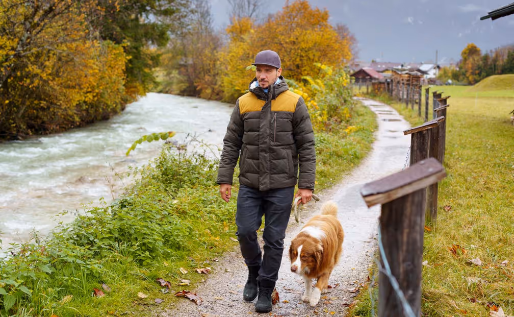 Felix Neureuther geht mit seinem Hund auf einem Kiesweg im Herbst spazieren