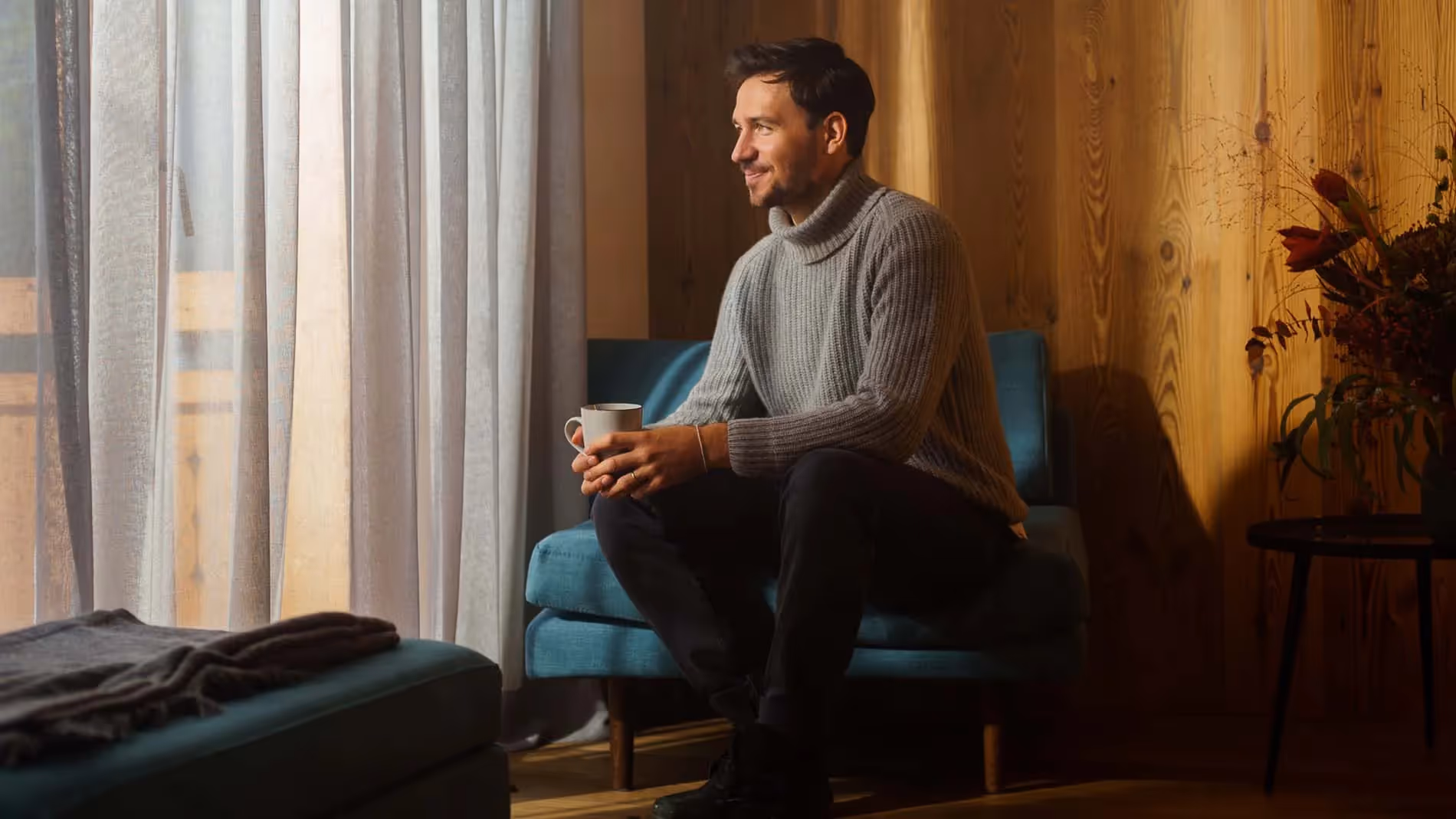 Felix Neureuther sitzt mit einer Tasse in der Hand auf einer Couch