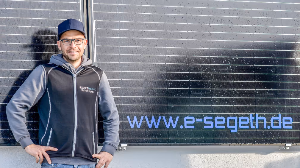 Michael Segeth vor dem Betriebsgebäude und dem Logo im Hintergrund.