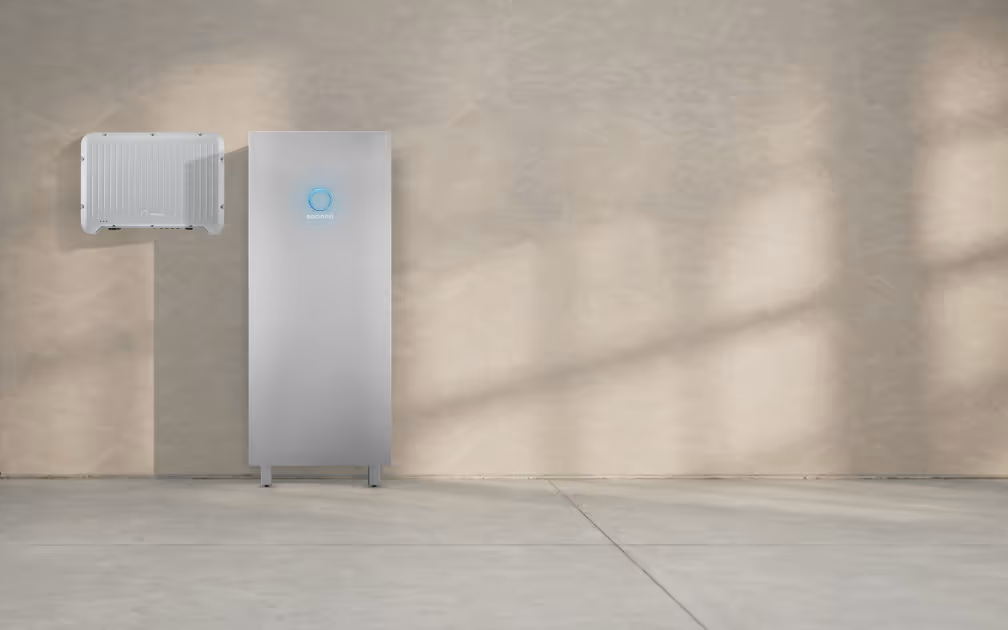 Die neue sonnenBatterie 10 hybrid vor einer schlichten Betonwand, links daneben der Wechselrichter sonnenInverter