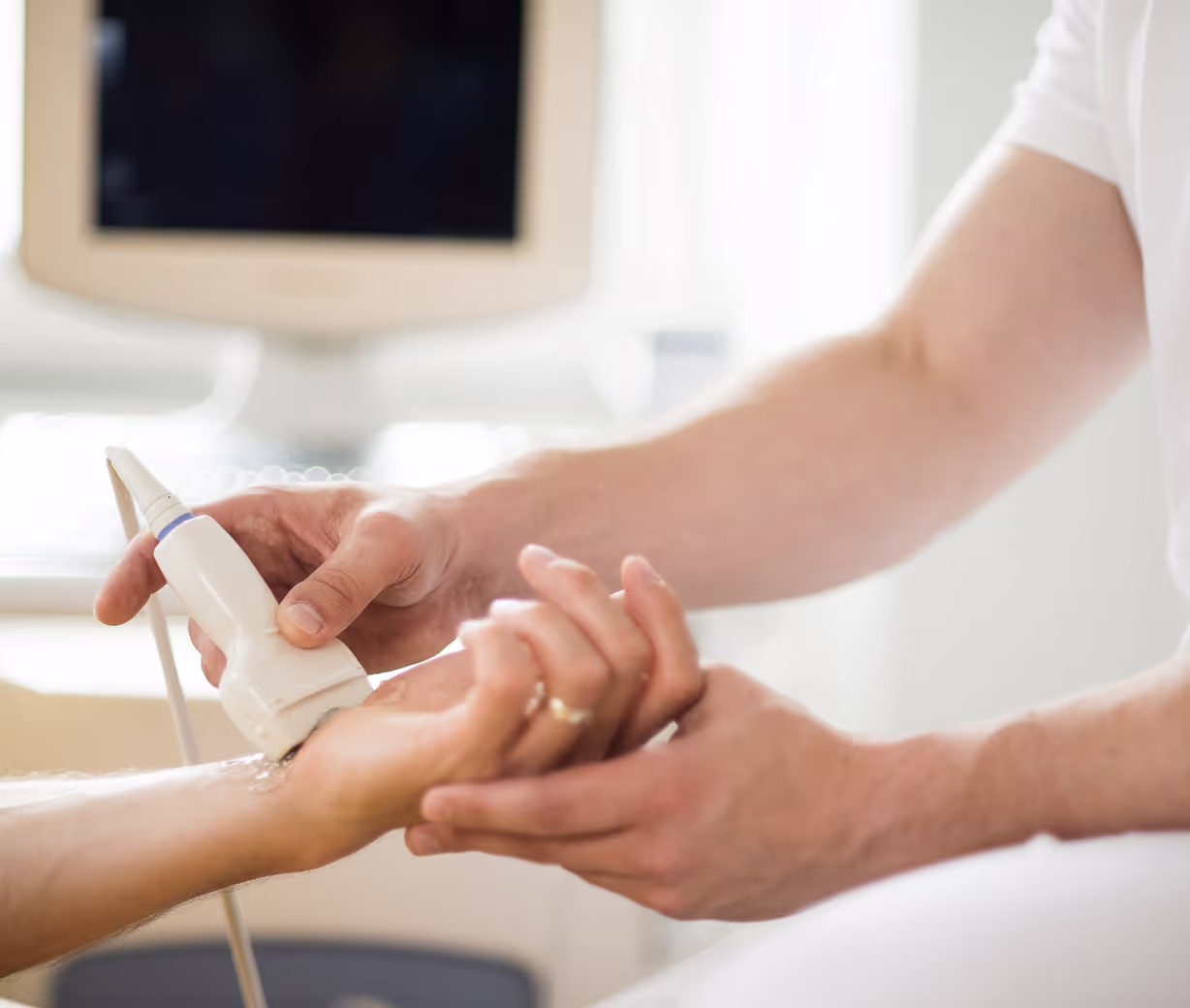 Ärztliche Behandlung an der Hand eines Patienten in einer orthopädischen Praxis.