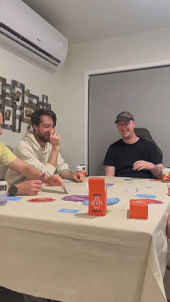 Four guys playing cockfight around a table.