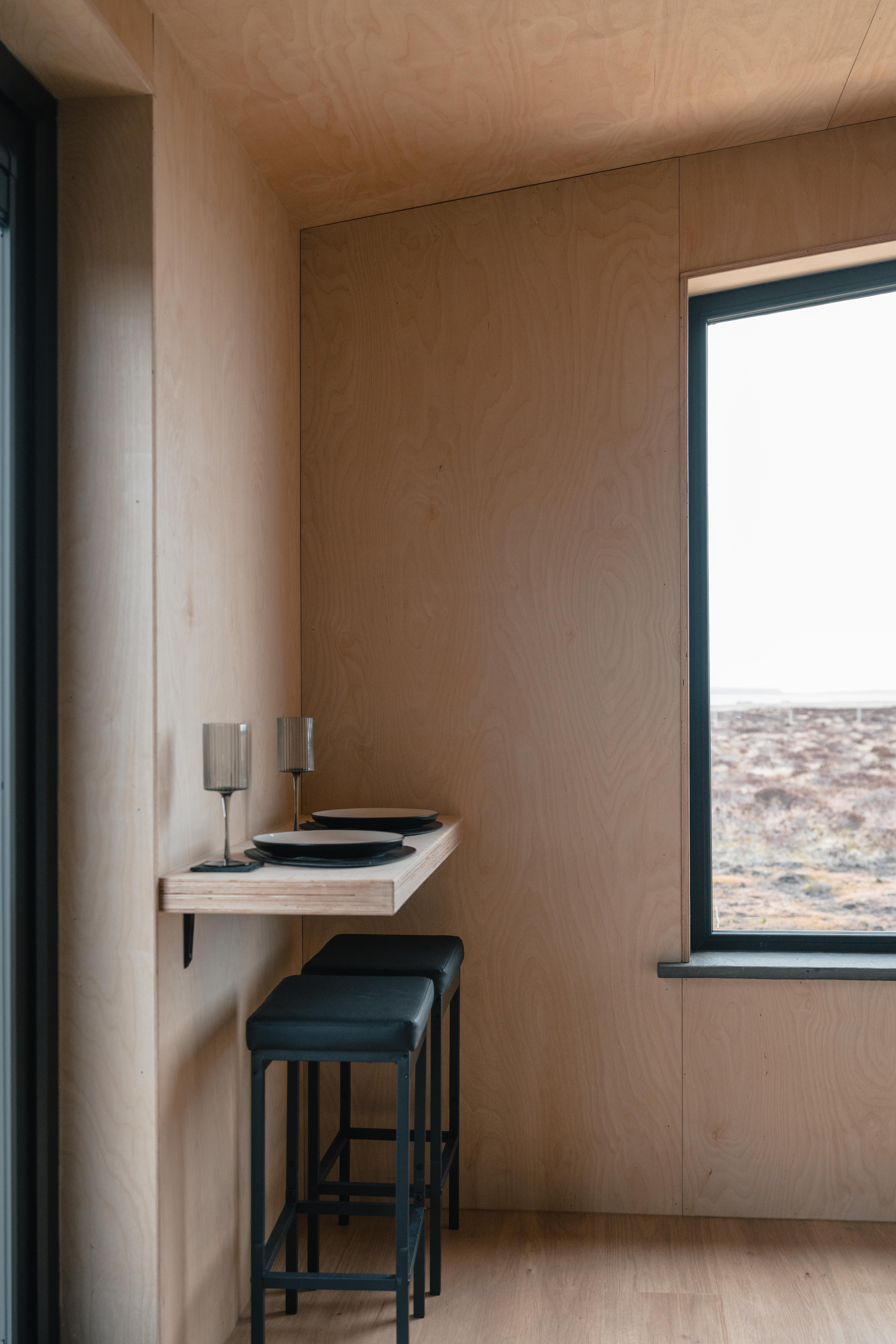 Modern bathroom with wooden floor, white vessel sink on dark cabinet, illuminated rectangular mirror, and white toilet with towels on top.