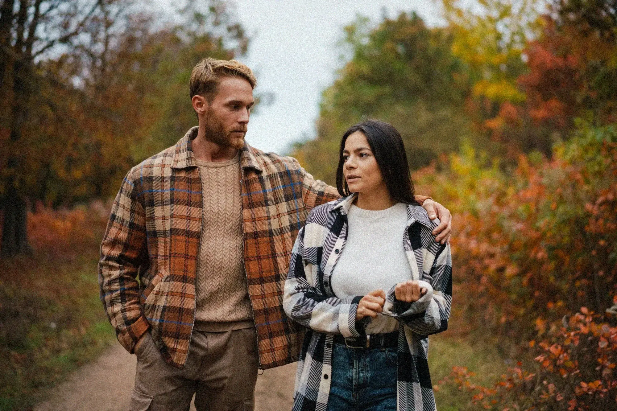 Couple walking and talking on a wooded path in fall